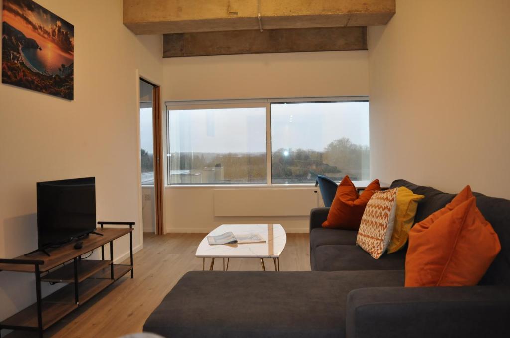 a living room with a couch and a tv at Station House Apartments in Milton Keynes
