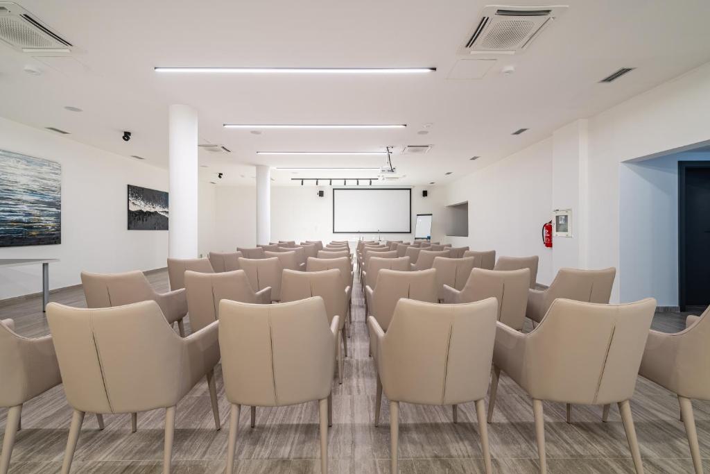 a room with white chairs and a projection screen at Miramare Hotel in Zadar
