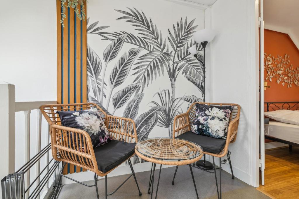 2 stoelen en een tafel op een balkon met een palmmuurschildering bij Chic and comfortable studio in Amiens