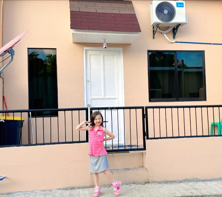 a little girl standing in front of a house at My Lovely Apartment in Dipolog