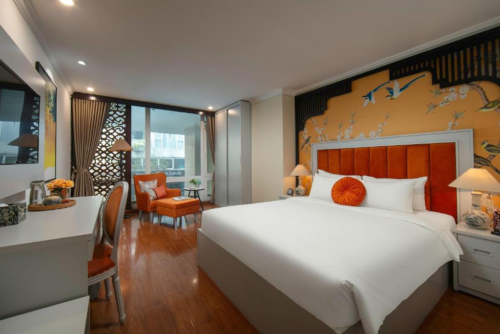 Un dormitorio con una gran cama blanca y un escritorio. en Serenata San de Hanoi Hotel, en Hanói
