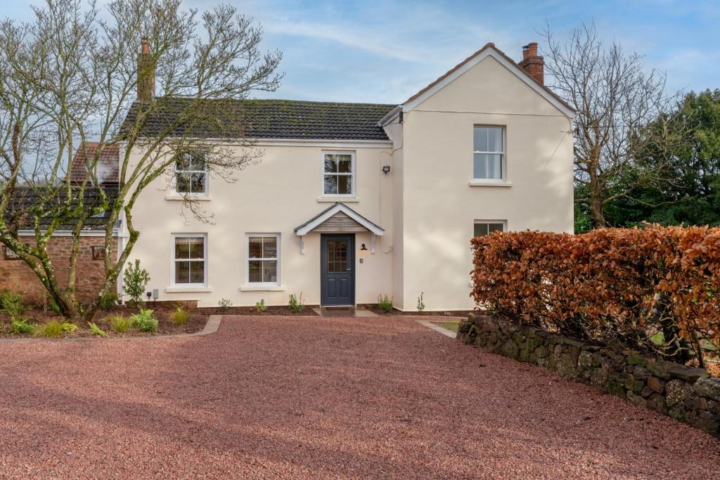 a white house with a gravel driveway at Deer Park Farmhouse in Lydney