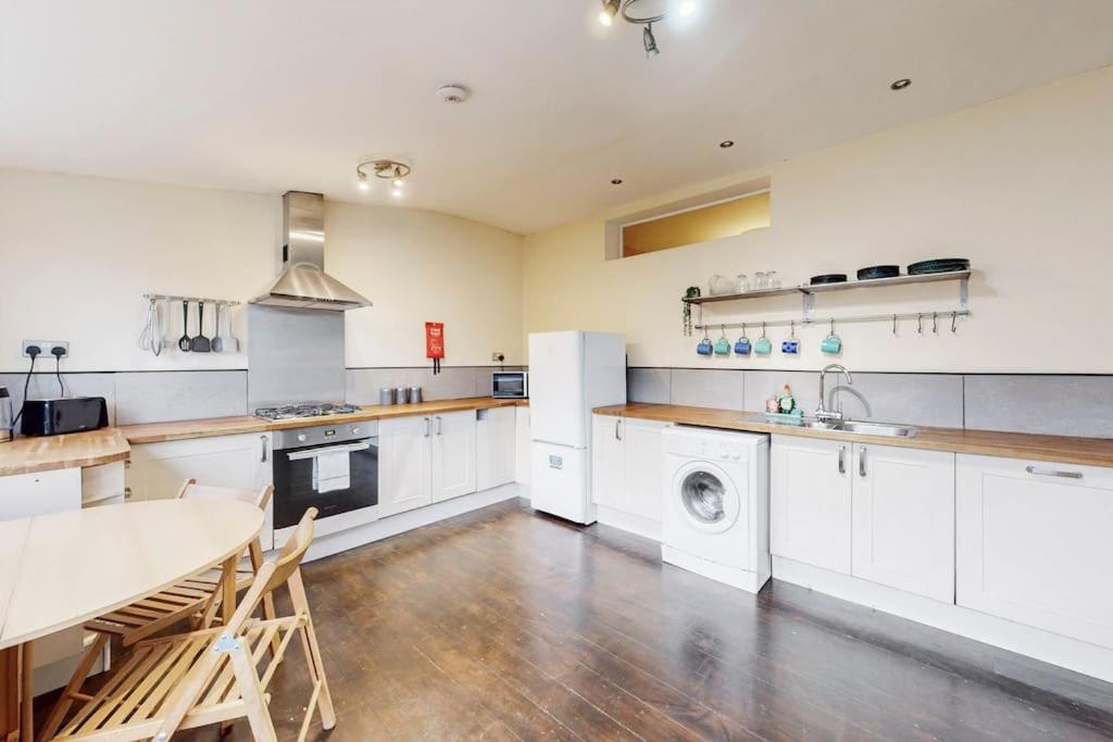 a large kitchen with white appliances and a table and chairs at Charming 1BD flat with a private garden in Leyton in London