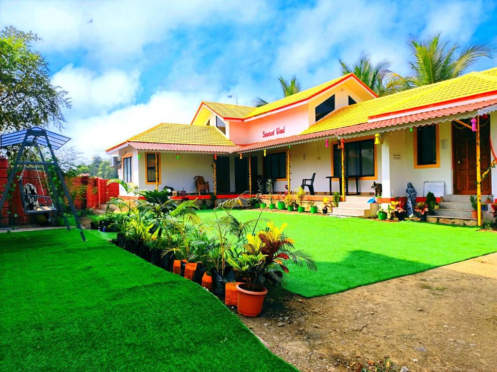 ein Haus mit grünem Rasen davor in der Unterkunft Suncrest Wood Stayz in Alibag