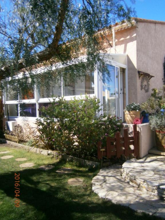 une maison blanche avec un arbre et une cour dans l'établissement maison climatisée dans jardin, à Torreilles