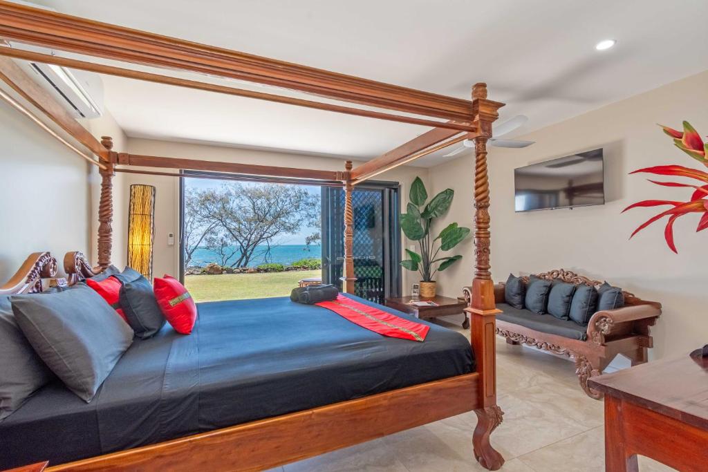 1 dormitorio con cama con dosel y ventana en Baligara Absolute Oceanfront Guest Suite en Bargara