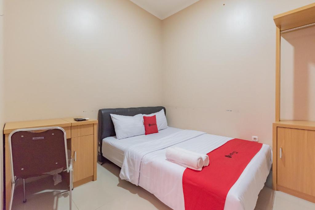 a small bedroom with a bed and a desk at RedDoorz Syariah near Exit Toll Subang in Subang