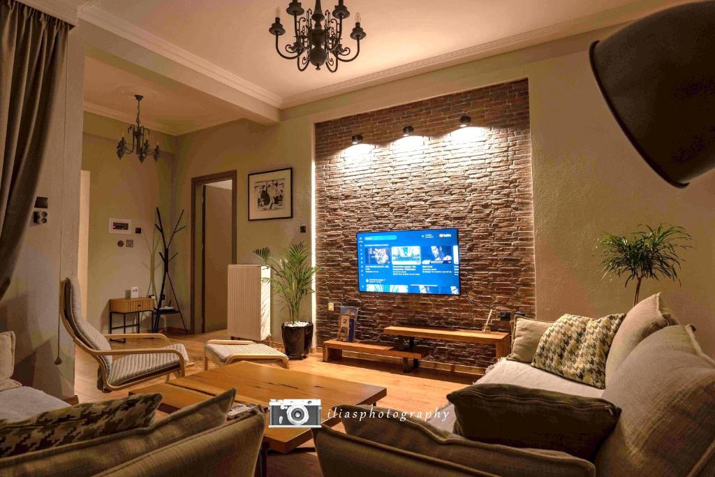 a living room with a tv on a brick wall at Living Life Apartment Komotini in Komotini