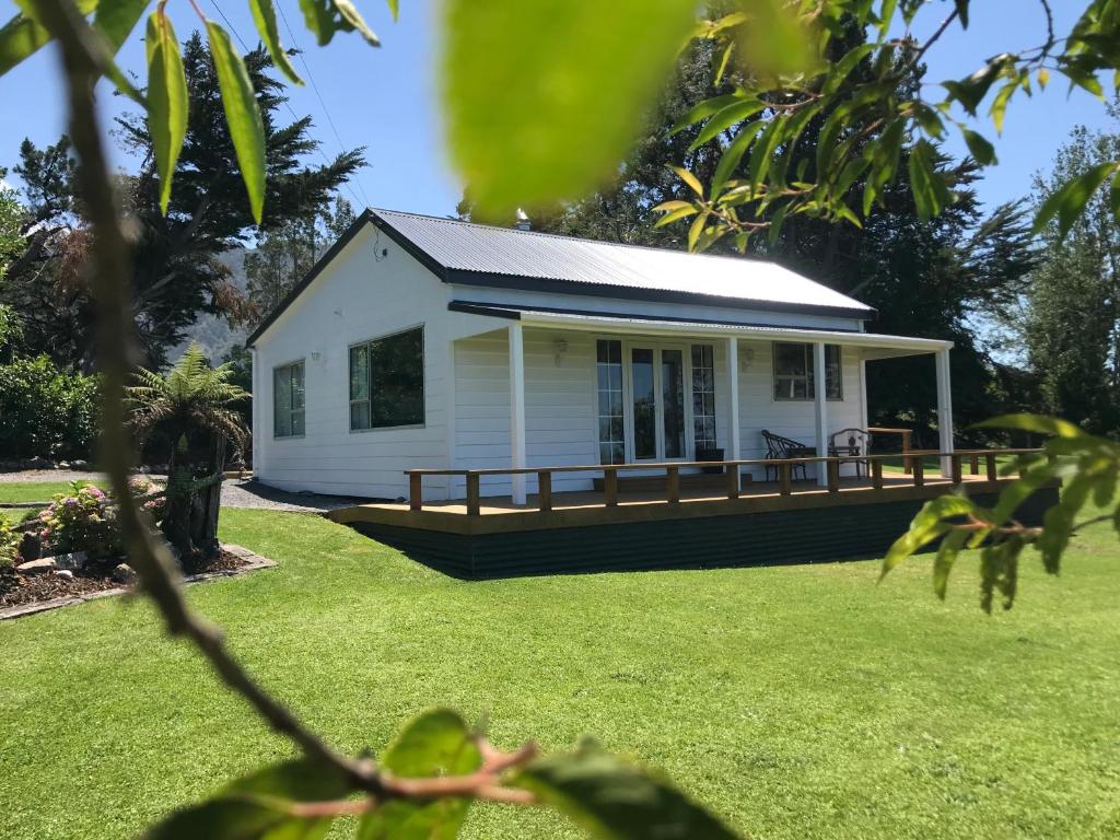 a small white house on a grass field at Kereru Cottage in Kaikoura