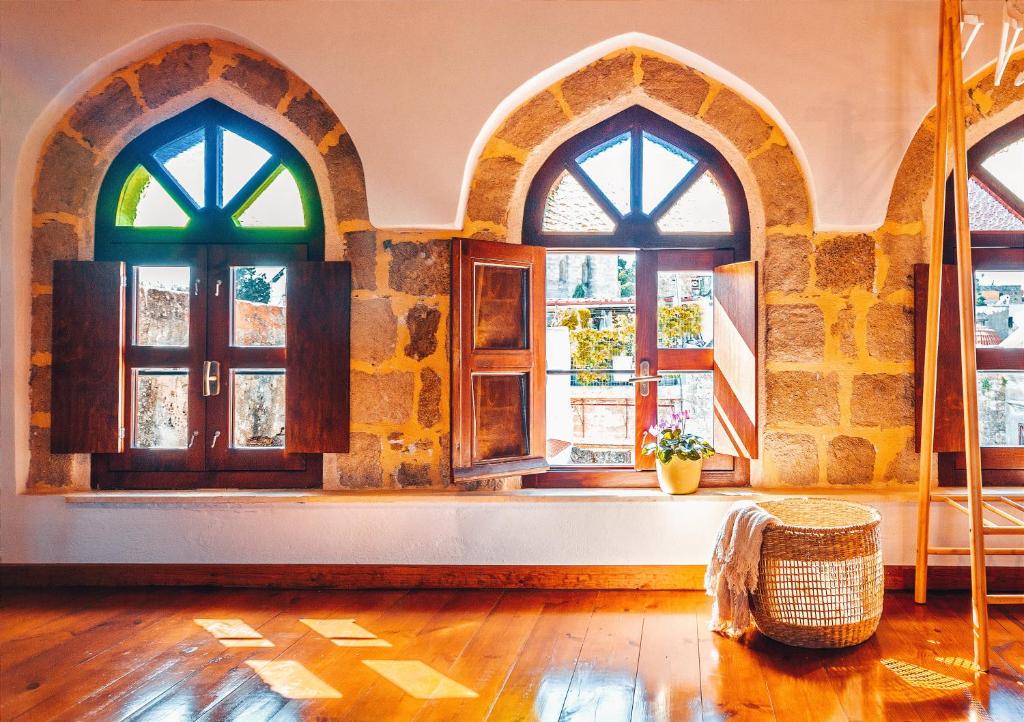 an empty room with three windows and a table at Mandorla Apartments in Rhodes Town