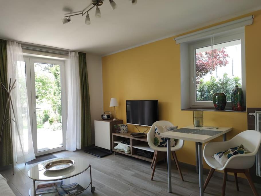 - un salon avec une table, des chaises et une télévision dans l'établissement Gemütliches Garten-Apartment mit Bergblick, à Murnau am Staffelsee