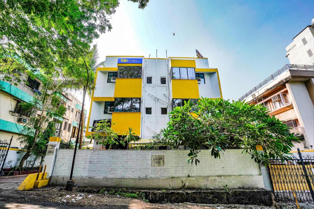 un edificio blanco y amarillo con árboles delante en FabExpress Bindra Elite en Bombay