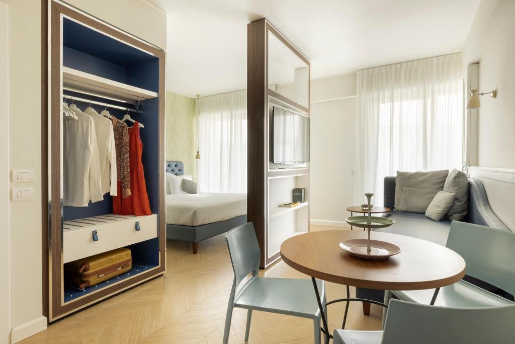 un soggiorno con tavolo e sedie e una camera da letto di BeSUITE Apartments a San Benedetto del Tronto