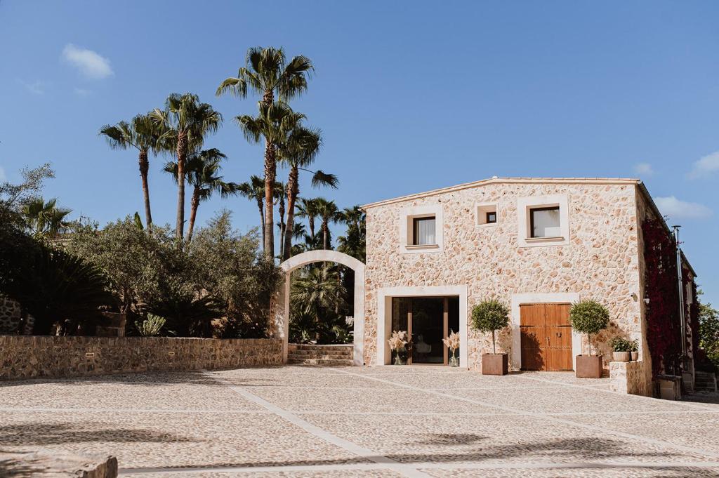 a large stone house with palm trees in the background at Sa Talaia Blanca in Muro