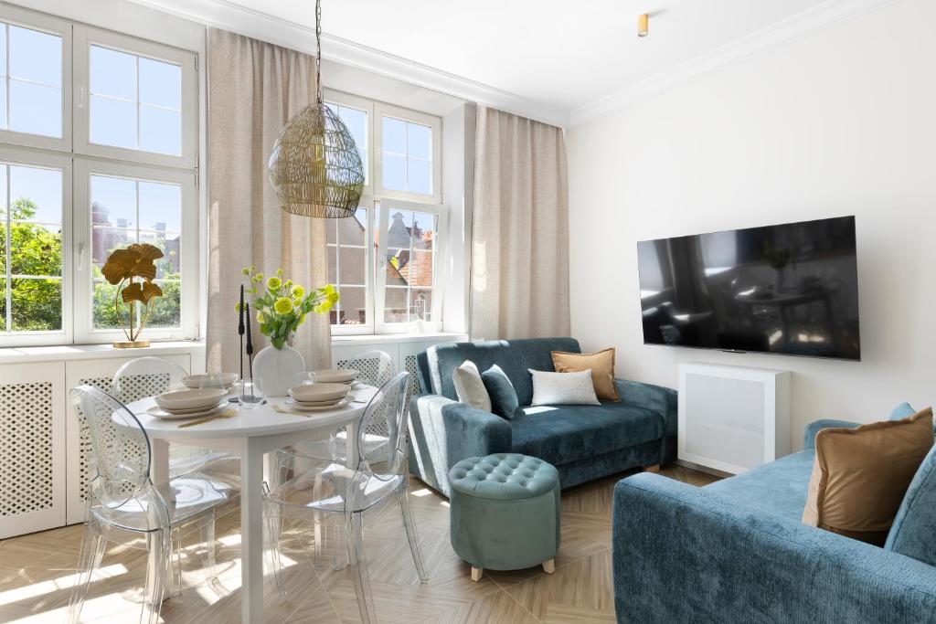 a living room with a blue couch and a table at Elite Apartments Mariacka Premium in Gdańsk