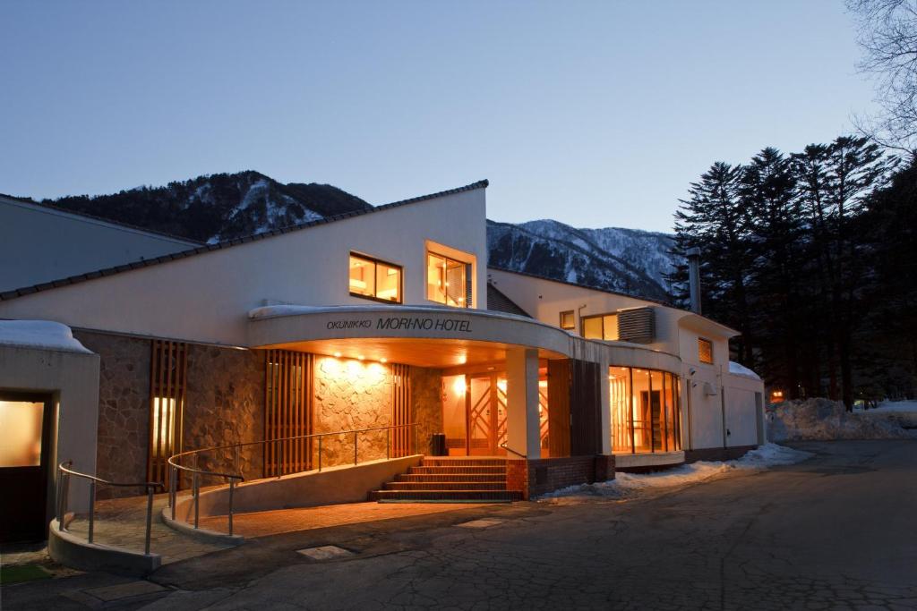 uma casa com uma escada em frente a um edifício em 奥日光森のホテル em Yumoto