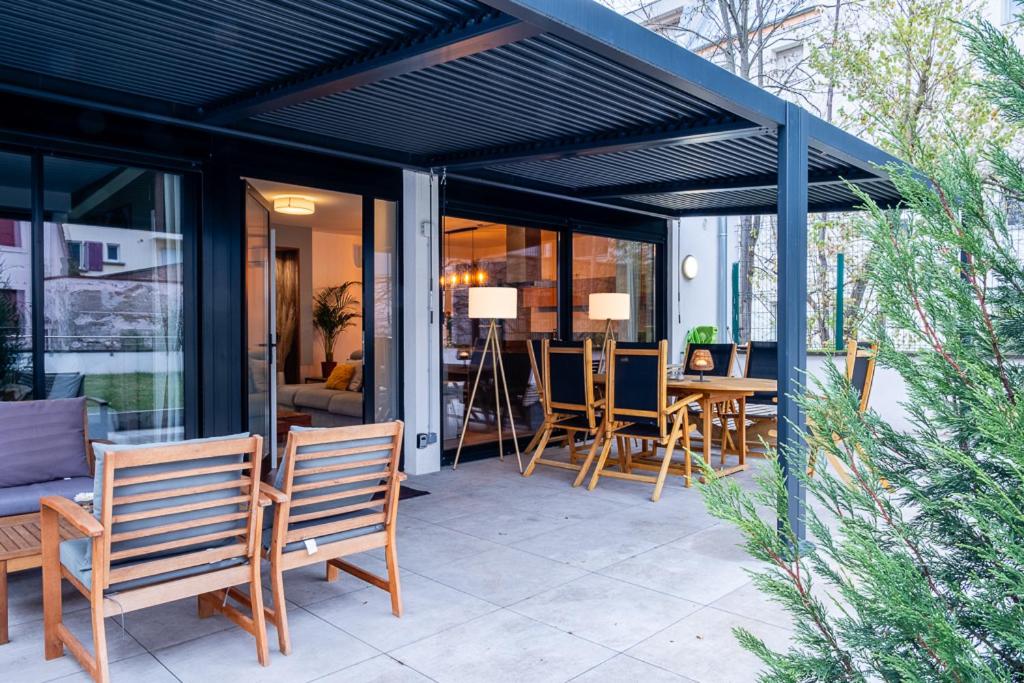a covered patio with chairs and a table with a table at Appartement Cosy Jardin et Terrasse in Strasbourg