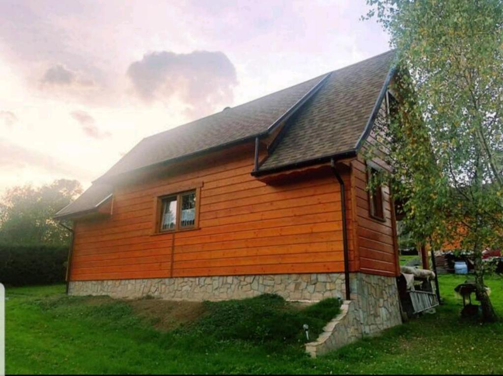 a small wooden house with a gambrel roof at Wrzos Chata w Beskidach in Kamesznica