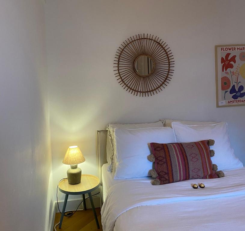 een slaapkamer met een wit bed, een lamp en een spiegel bij Chez Sybi in Amsterdam