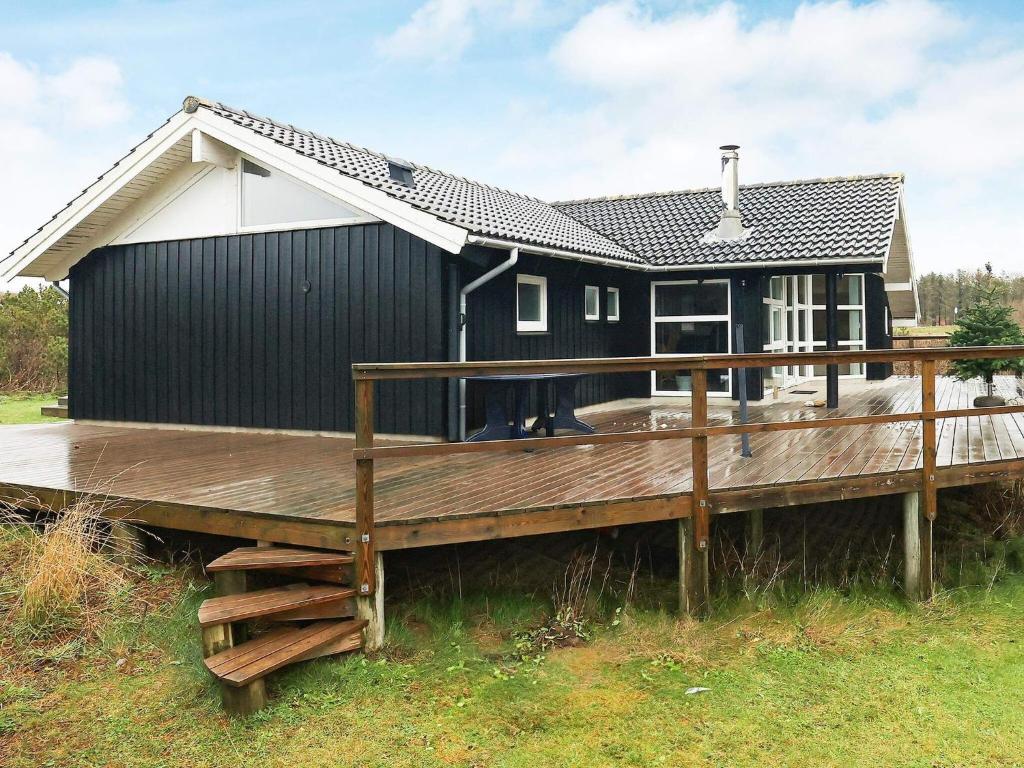 ロッケンにあるThree-Bedroom Holiday home in Løkken 81の木製デッキ付き白黒家屋