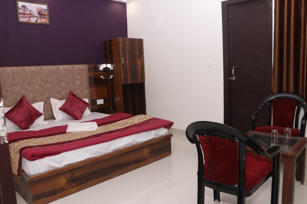 a bedroom with a bed and a chair and a table at Hotel Grand Exotica in Haridwār