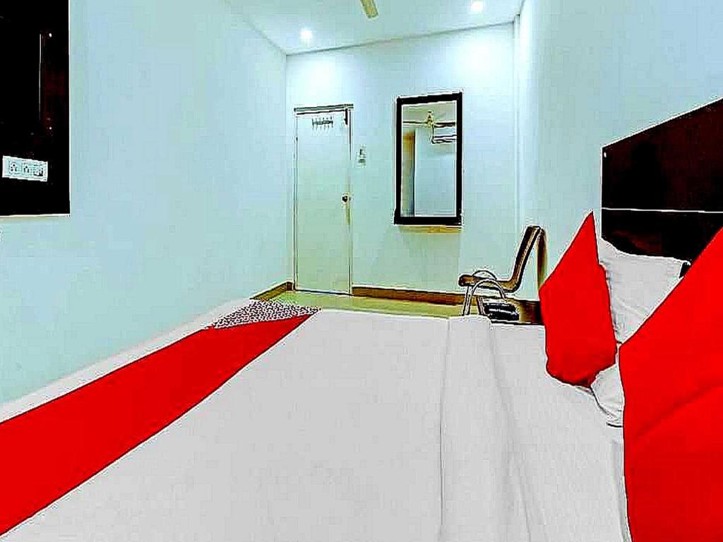 a bedroom with a large bed with red pillows at Hotel O Meridian Grand in Shamshabad