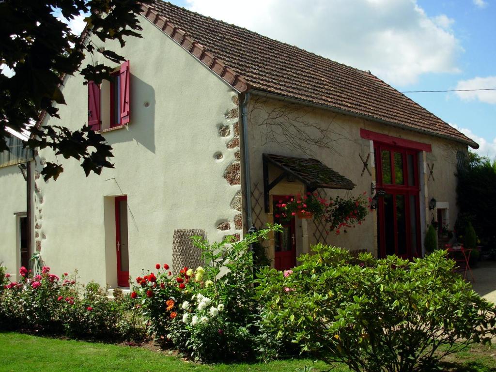 a white house with red windows and flowers at La Grange du Bourg in Deneuille-les-Mines