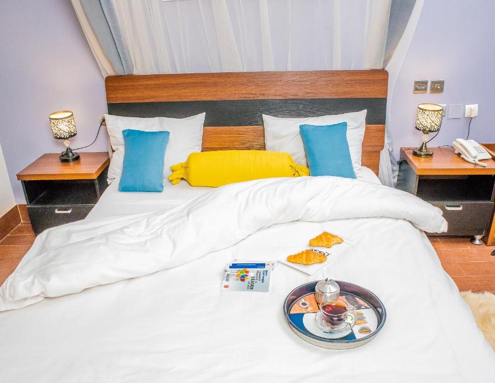 a white bed with a tray of food on it at Hotel Hibiscus in Bujumbura