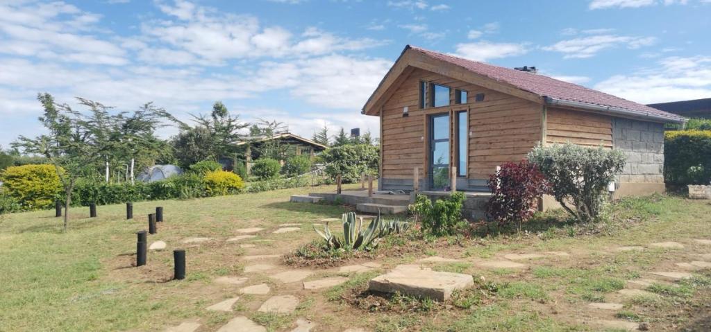 a small wooden house in a field with a garden at Elwai Centre Wood Cabins - Couples' hideout in Heni Village