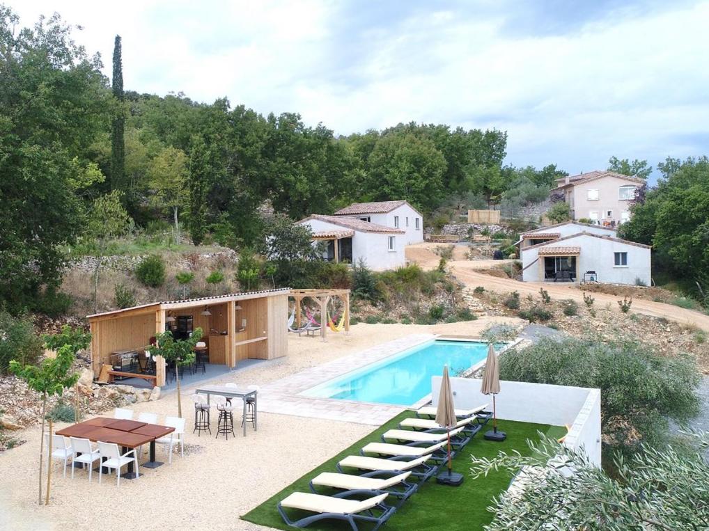 une piscine avec des chaises longues et une maison dans l'établissement Le Quartier - 4 alleenstaande gites, à Banne
