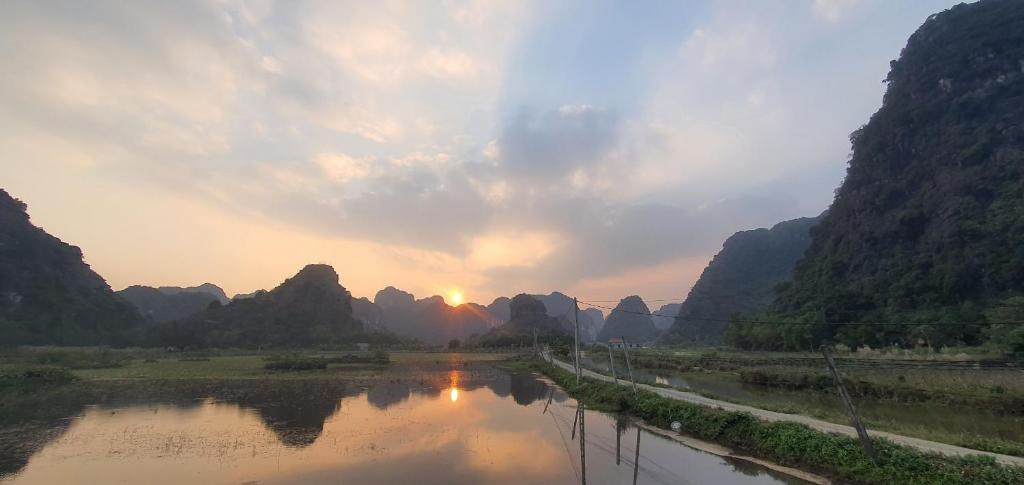 a river with mountains and the sunset in the background at Ninh Binh Truong Nhan homestay in Ninh Binh