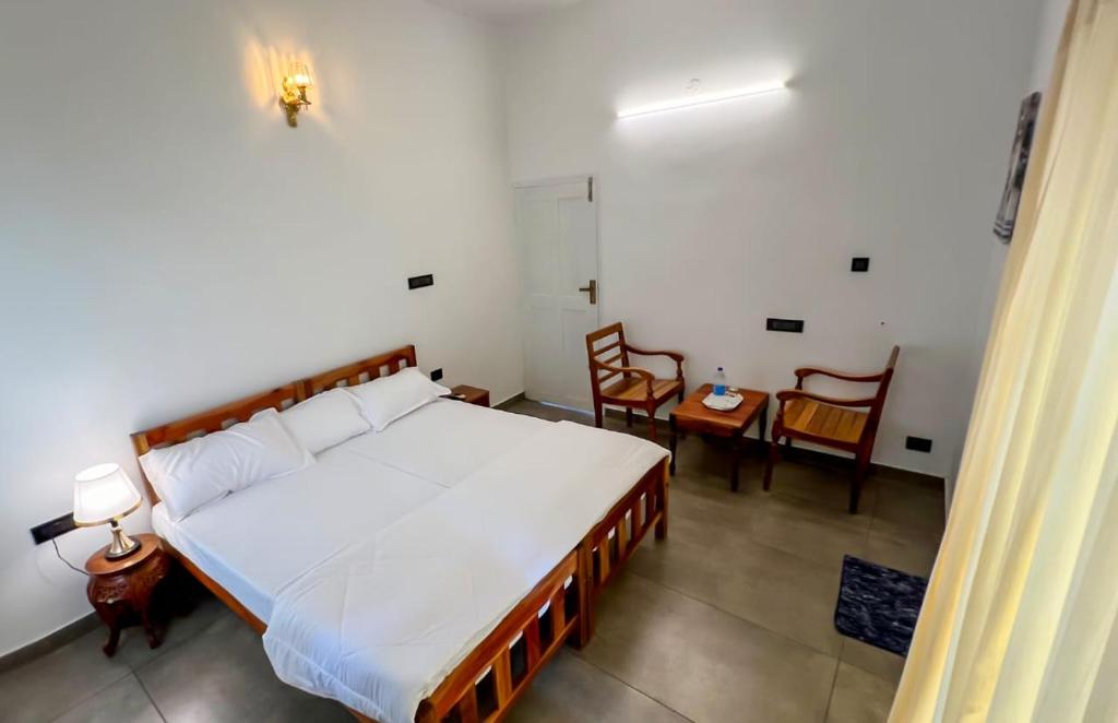um quarto com uma cama, uma mesa e cadeiras em ELZAS FORTINN Homestay Fortkochin,kochi em Cochin