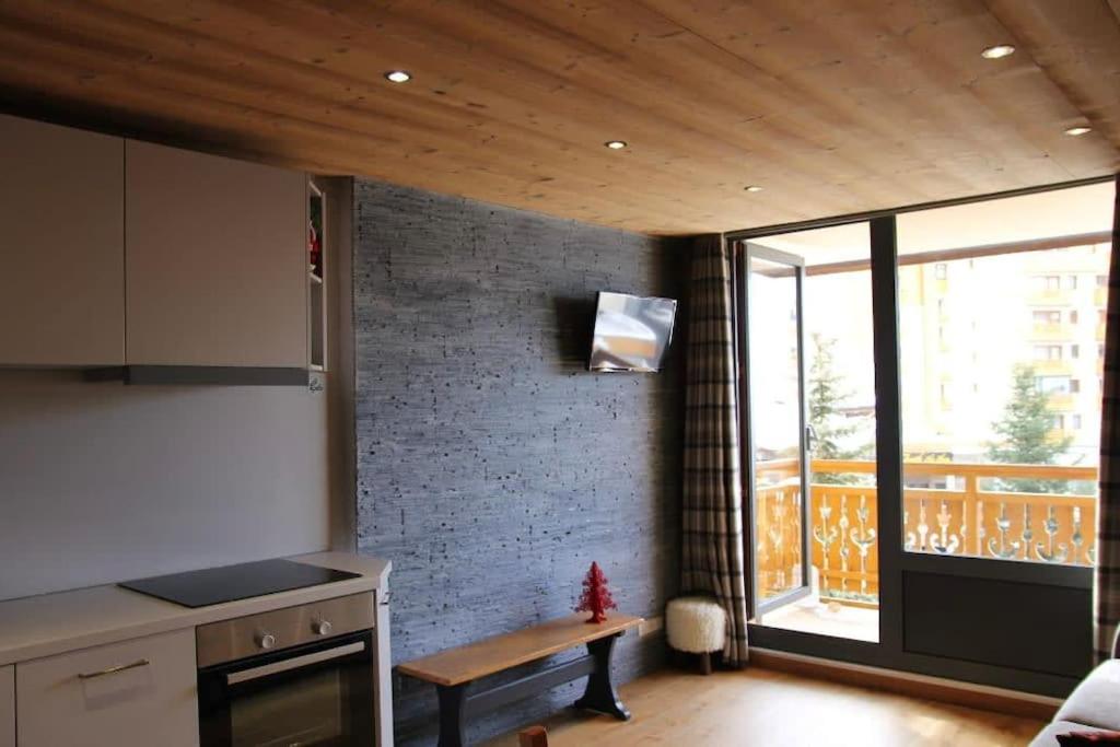 eine Küche mit einer Theke, einem Tisch und einem Fenster in der Unterkunft Cozy and Spectacular Condo VT in Val Thorens