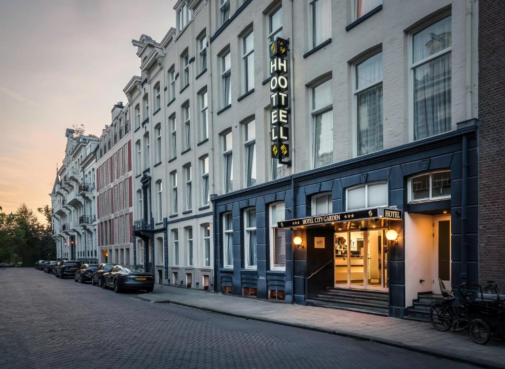 eine Reihe von Gebäuden auf einer Straße mit parkenden Autos in der Unterkunft Hotel City Garden Amsterdam in Amsterdam