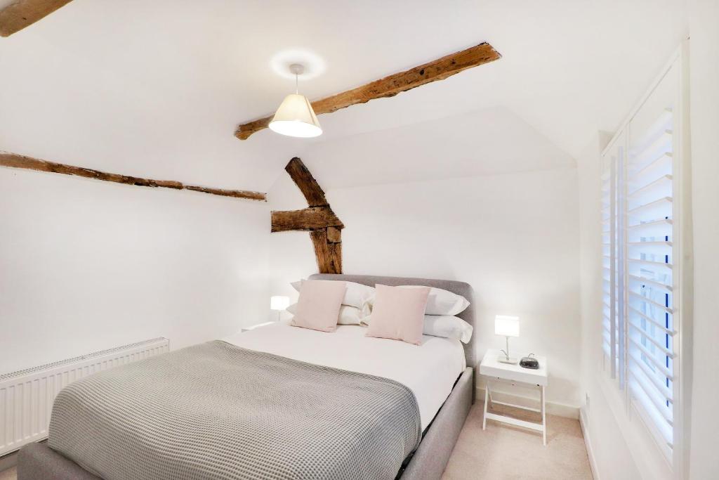 a white bedroom with a bed and a cross on the wall at Perfectly Presented Cottage Pass the Keys in Robertsbridge