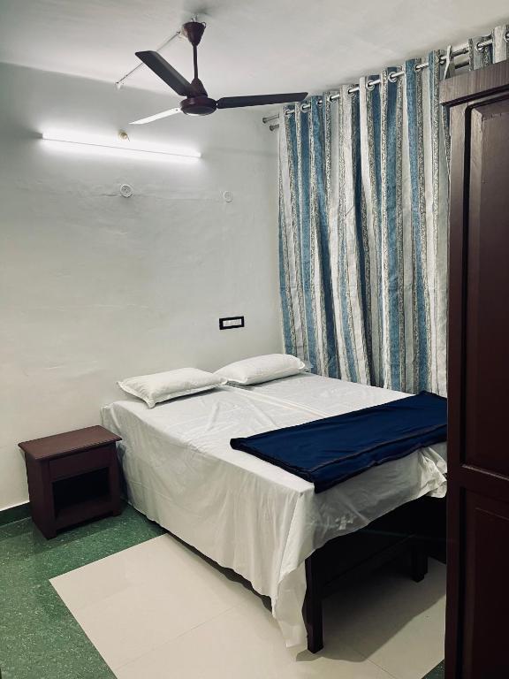 - une chambre avec un lit et un ventilateur de plafond dans l'établissement Puthookkadans Mareena Lodge, à Kottayam