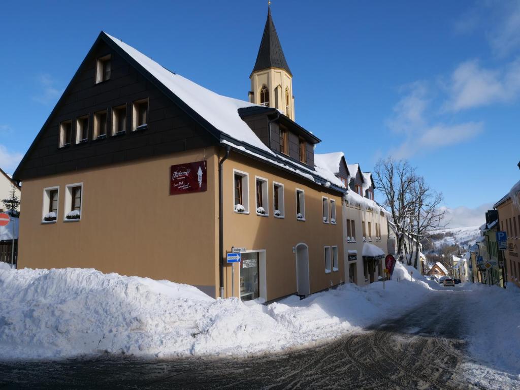 ein Gebäude mit einem Uhrturm auf einer verschneiten Straße in der Unterkunft Ferienvermietung Engelstädter in Kurort Oberwiesenthal
