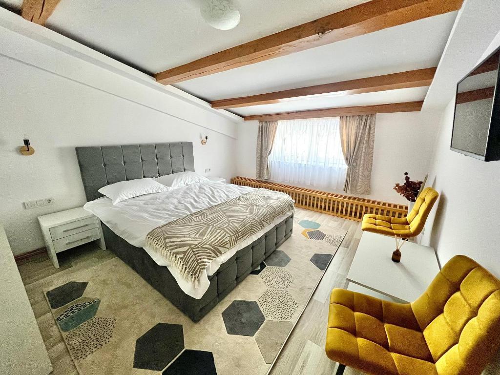 - une chambre avec un grand lit et une chaise jaune dans l'établissement Parc Vatra Dornei 3 - Family & couples, à Vatra Dornei