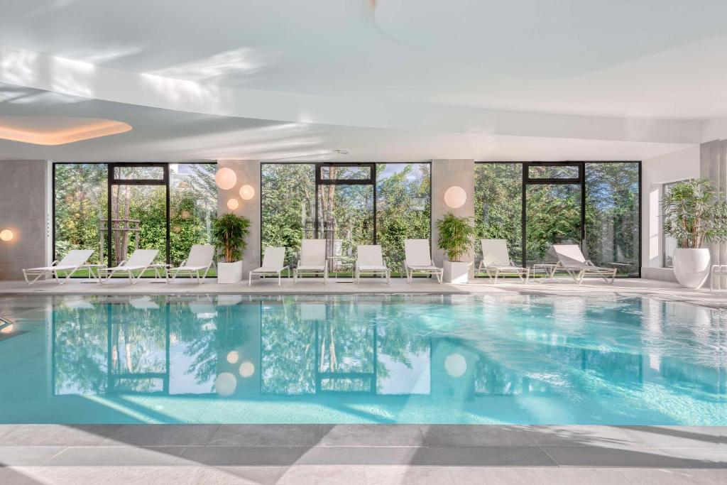 a pool in a hotel with chairs and windows at GOLDEN TULIP LYON OUEST TECHLID Hotel & Spa in Limonest