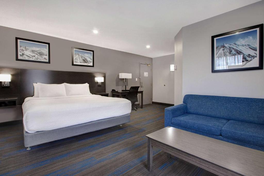 a hotel room with a bed and a blue couch at Days Inn by Wyndham Barrie in Barrie