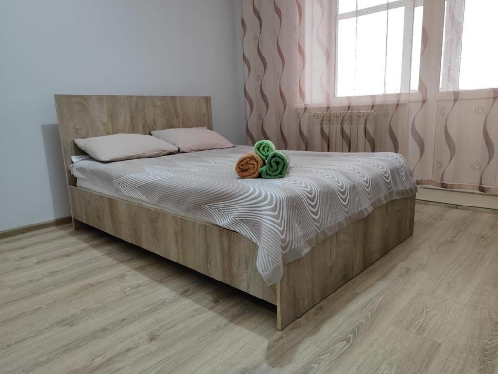 a bedroom with a bed with a wooden headboard at Квартира посуточно in Kokshetau