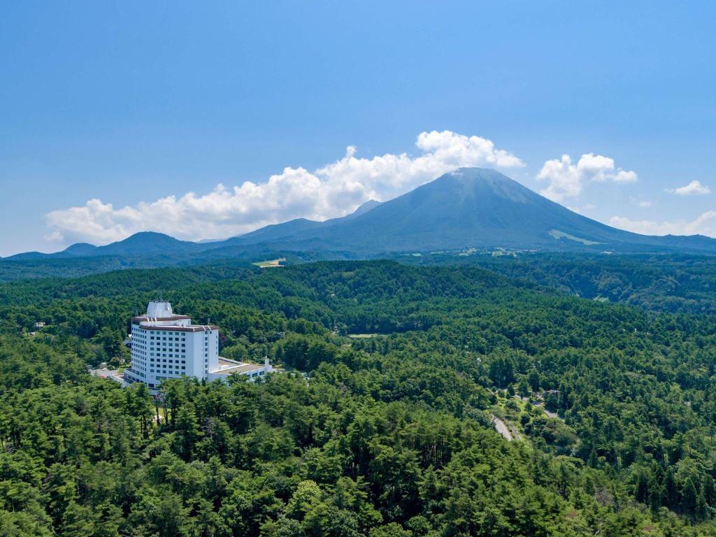 a building in the trees with a mountain in the background at Mercure Tottori Daisen Resort & Spa in Daisen