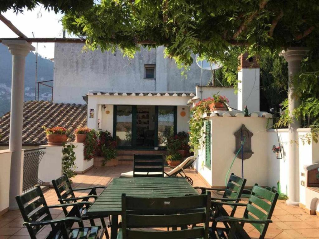 un patio al aire libre con una mesa verde y sillas en Villa Piccinina A pochi passi da Villa Eva, en Ravello