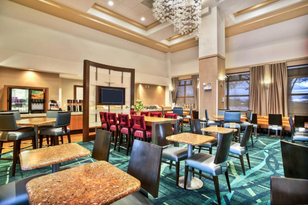 ein Restaurant mit Tischen und Stühlen und einem Flachbild-TV in der Unterkunft SpringHill Suites by Marriott Chicago Southwest at Burr Ridge Hinsdale in Burr Ridge