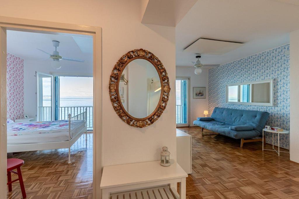 een woonkamer met een spiegel en een blauwe bank bij Seafront Residence Punta in Piran