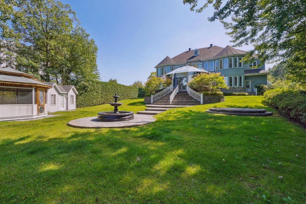 a house with a fountain in the middle of a yard at Villa Laval Bord de l'eau in Laval