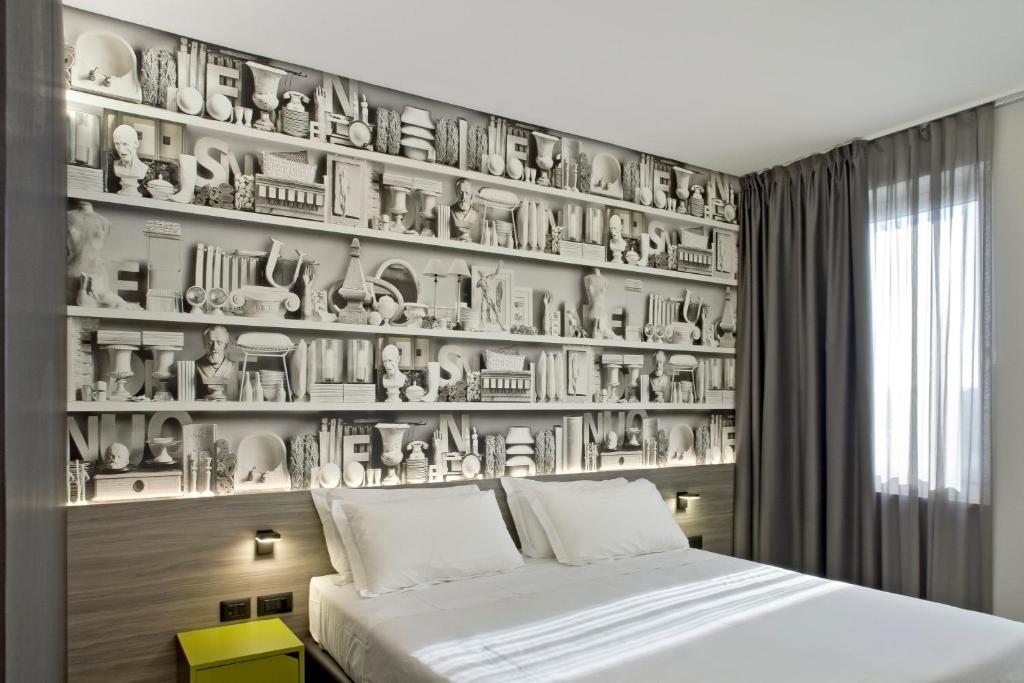 Hotel Friuli في أوديني: غرفة نوم بها جدار من الأطباق وسرير