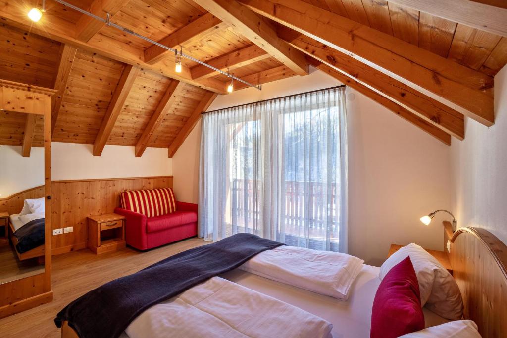 a bedroom with a bed and a red chair at Apartments Perfila Ferienchalet in Valdaora