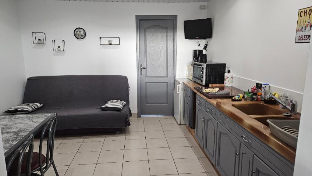 een woonkamer met een bank en een keuken bij Logement au calme, avec vue dégagée in Ardoix