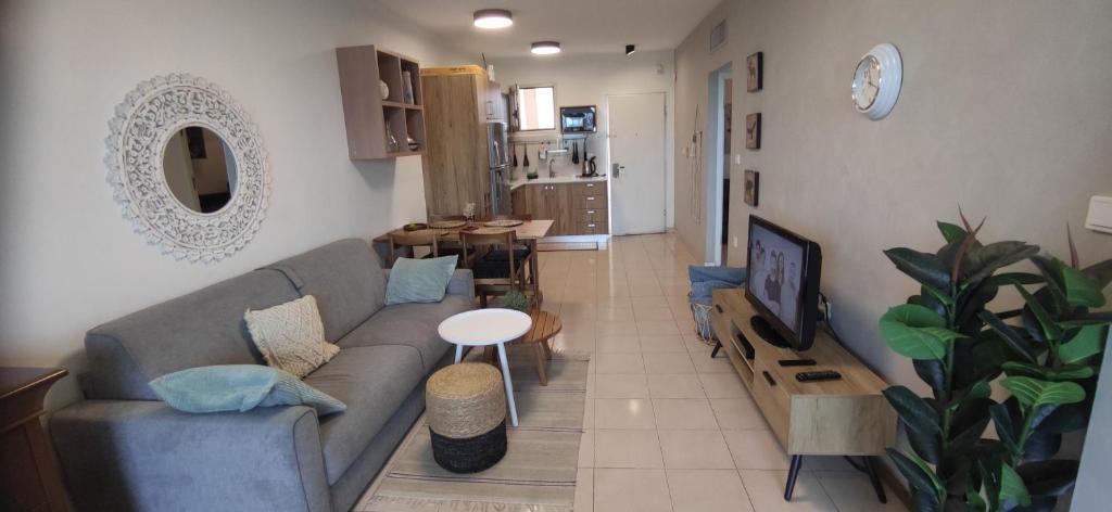 a living room with a couch and a table and a tv at Neot Golf Caesarea Garden Apartment in Caesarea